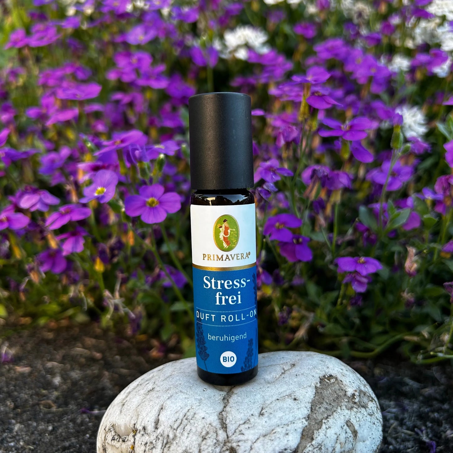 Stressfrei Duft-Roll-On steht auf einem Stein vor einer violett weissen Blumenwiese.