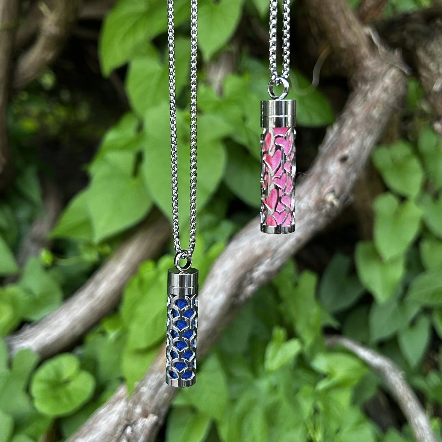 2 Halsketten mit Duftanhänger hängen nebeneinander an einem Baum