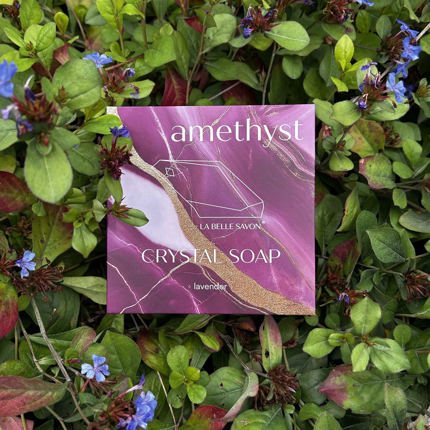 Die amethyst Crystal Soap liegt auf Blumen mit rot, grün und teils blauen Blättern.