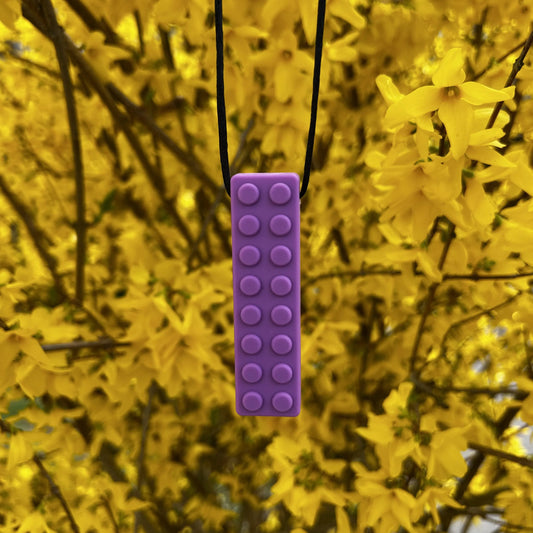 Beisserchen Kette in violett hängt am Ast eines Baumes mit gelben Blüten