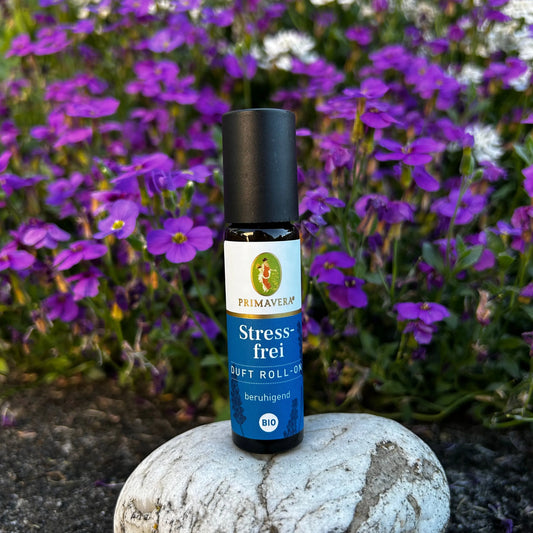 Stressfrei Duft-Roll-On steht auf einem Stein vor einer violett weissen Blumenwiese.
