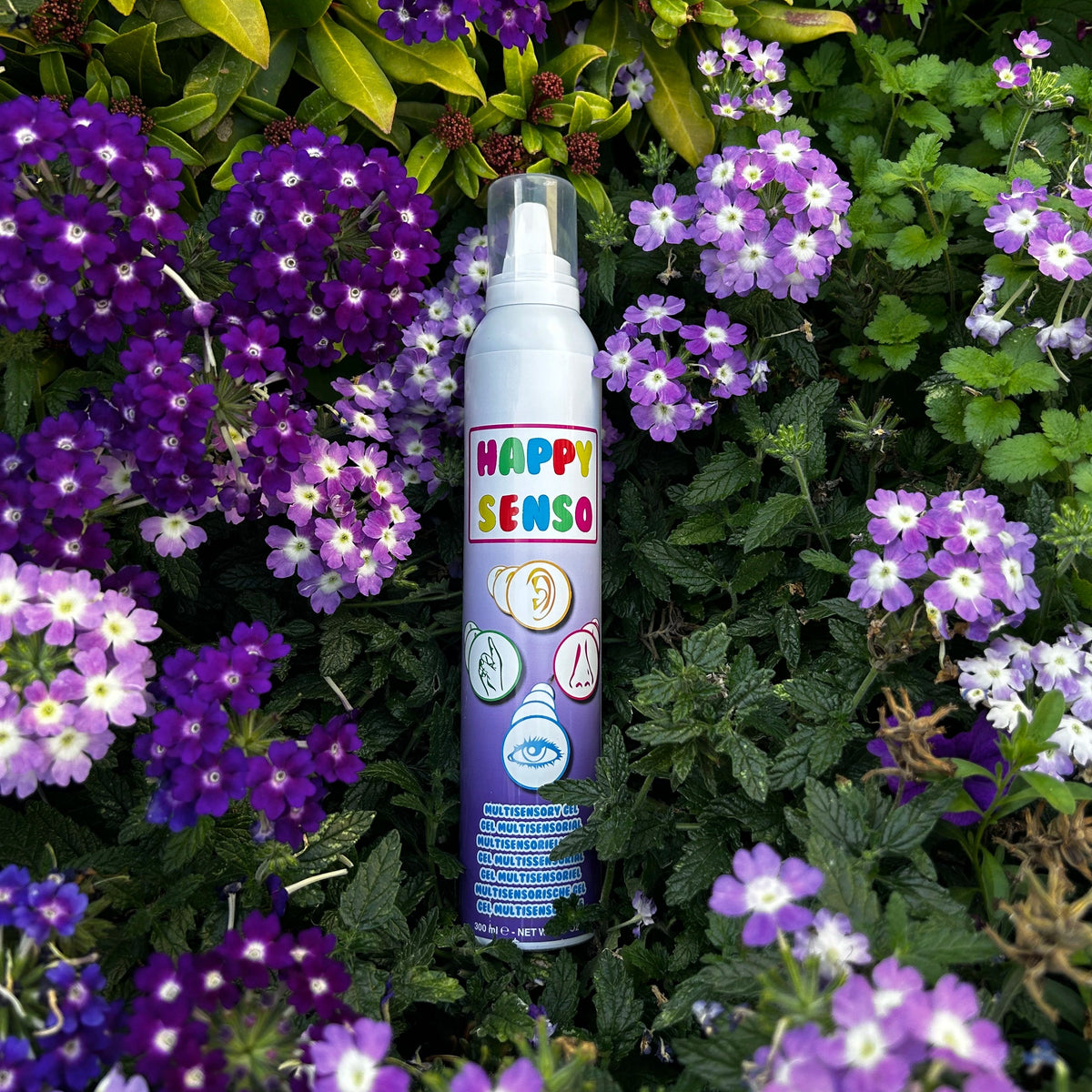 Happy Senso Schaum Spray (violett) liegt auf einem Busch mit violetten Blumen