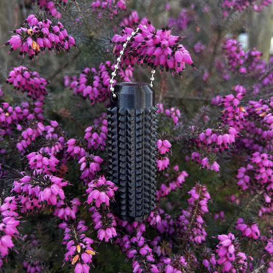 Pocketigel, an einer Pflanze mit pinkigen Blumen hängend