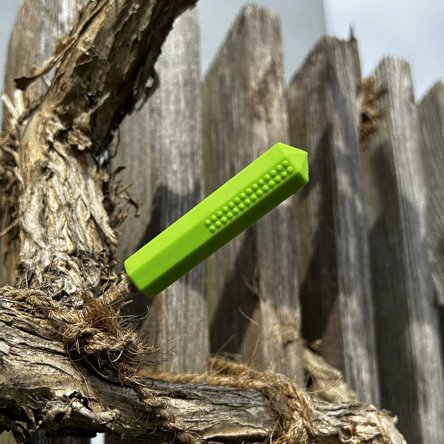 Grüner Kauaufsatz für einen Stift auf einem Holzigen Hintergrund.