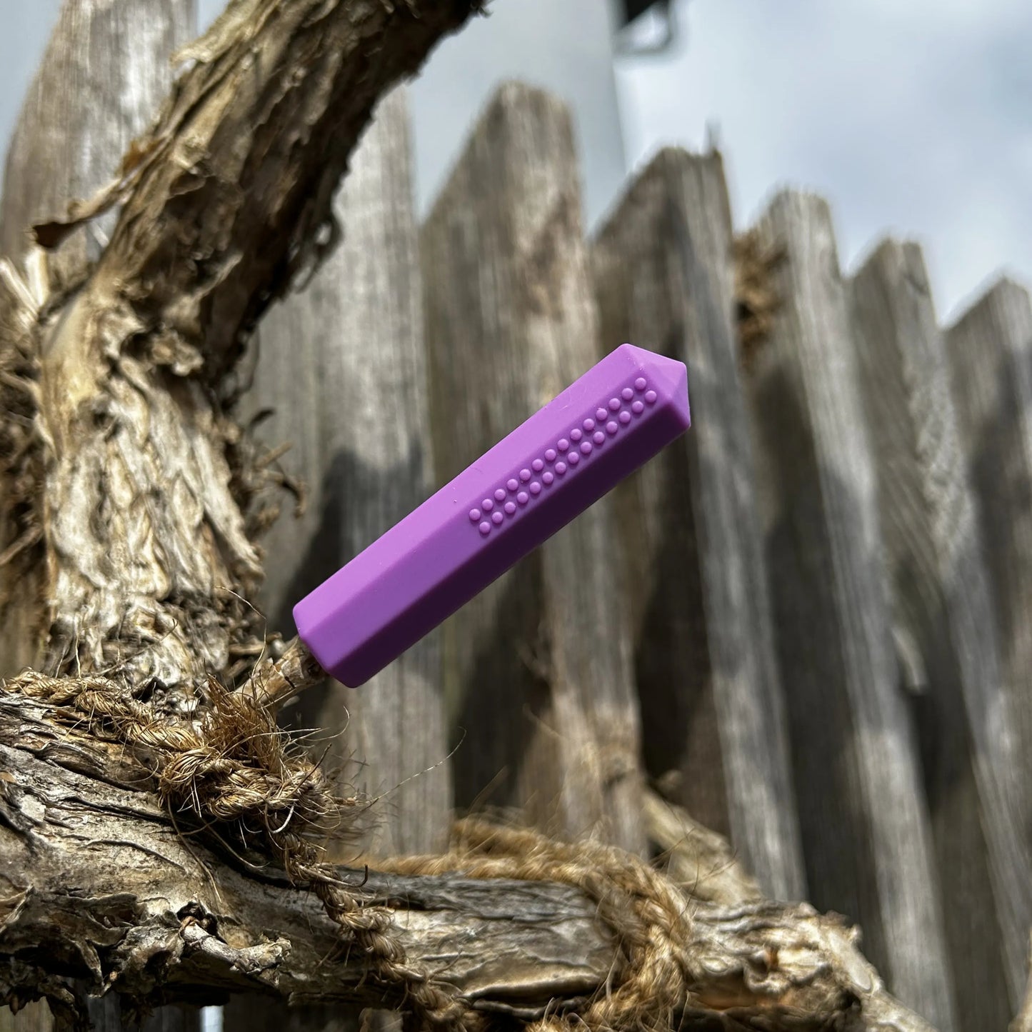 Violetter Kauaufsatz für einen Stift auf einem Holzigen Hintergrund.